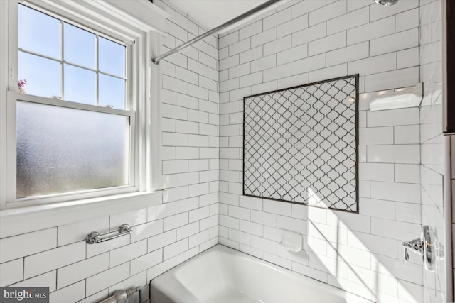 bathroom with tiled shower / bath, tile walls, and a healthy amount of sunlight