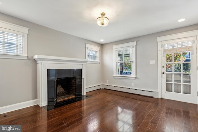 unfurnished living room featuring dark wood-type flooring, a tiled fireplace, and baseboard heating