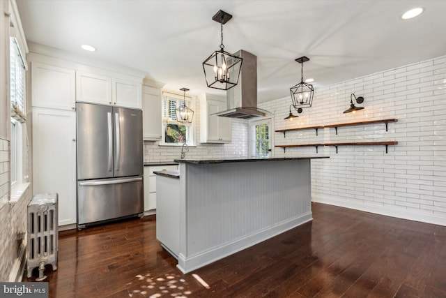 kitchen featuring island range hood, dark hardwood / wood-style floors, stainless steel fridge, white cabinets, and radiator heating unit