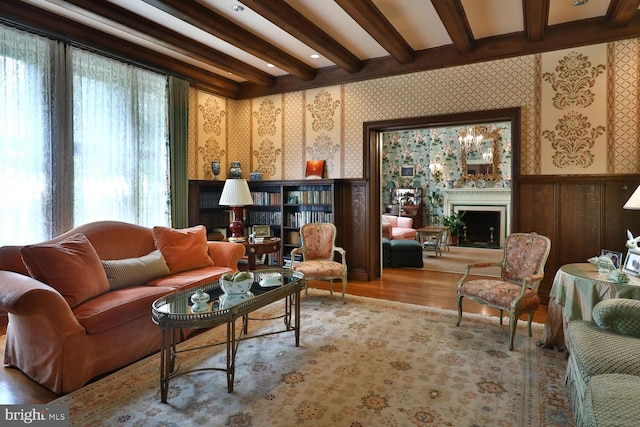 sitting room featuring beamed ceiling, wainscoting, a fireplace, and wallpapered walls