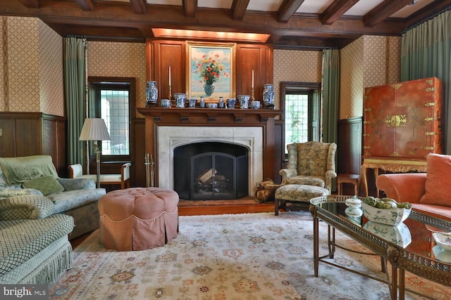 sitting room with a wainscoted wall, beamed ceiling, a fireplace, and wallpapered walls