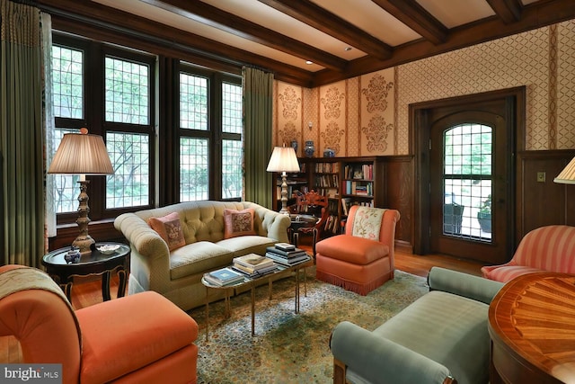 sitting room with wallpapered walls, beam ceiling, and wainscoting