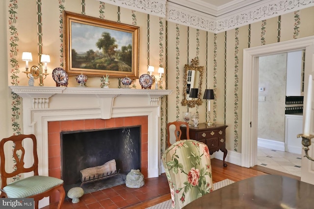 living area featuring a fireplace, wallpapered walls, and baseboards