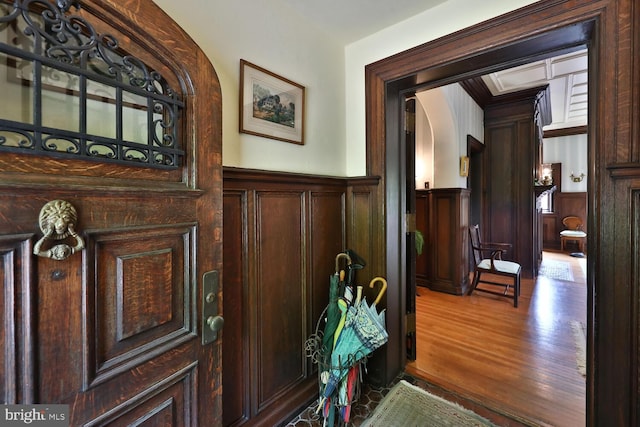 doorway featuring wood finished floors, arched walkways, and wainscoting