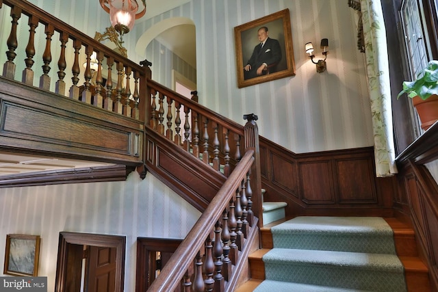 staircase with a wainscoted wall and wallpapered walls