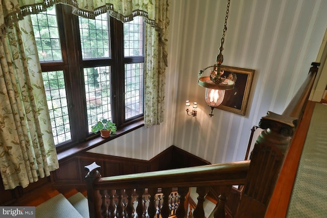 staircase featuring wallpapered walls and wainscoting