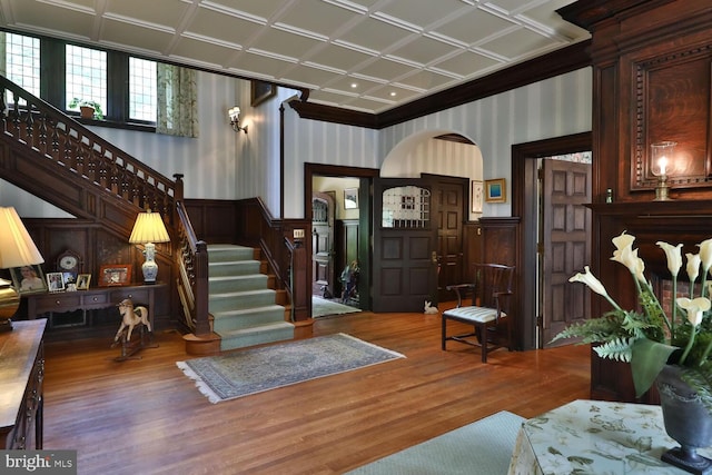 entryway featuring a wainscoted wall, stairway, wallpapered walls, and wood finished floors