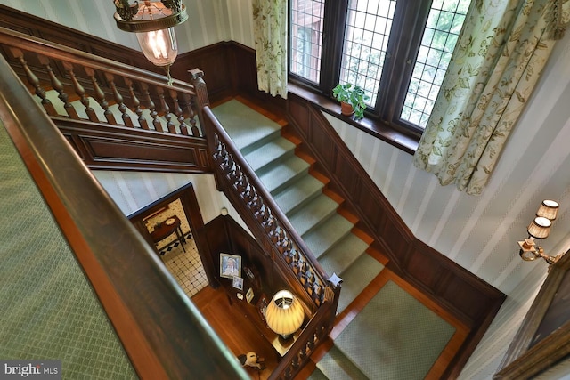 stairs with a wainscoted wall and wallpapered walls