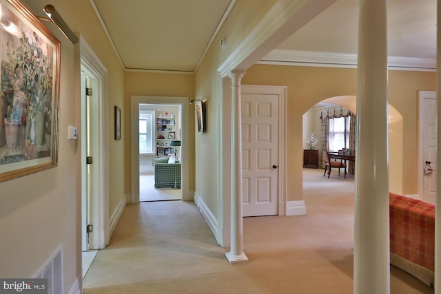 hallway with crown molding, decorative columns, light colored carpet, and visible vents