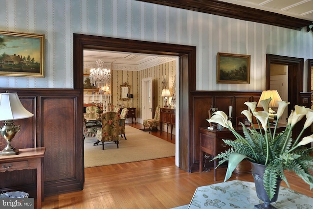 corridor featuring wallpapered walls, an inviting chandelier, and wood finished floors