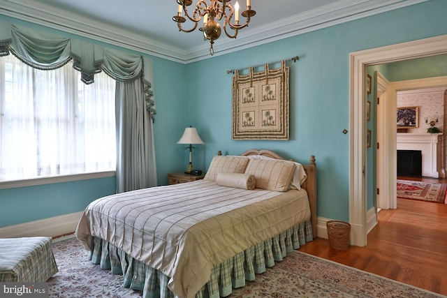 bedroom featuring baseboards, wood finished floors, a fireplace, and crown molding