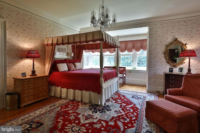 bedroom featuring wood finished floors, baseboards, wallpapered walls, an inviting chandelier, and ornamental molding