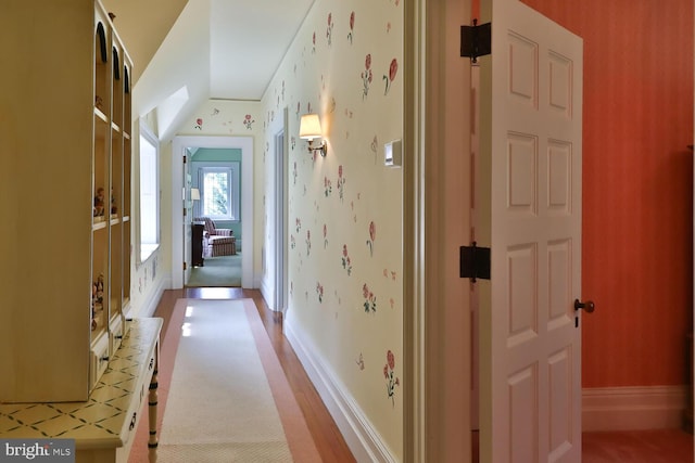 hall with baseboards and wallpapered walls