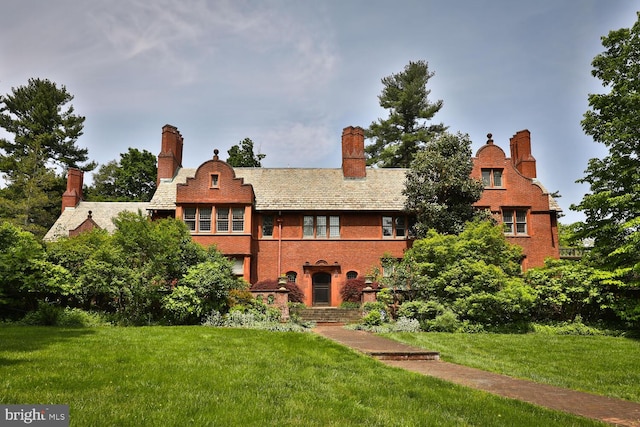 rear view of property with a yard, a high end roof, and brick siding