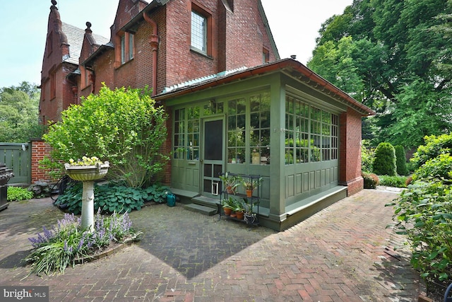 view of side of property featuring brick siding, entry steps, and a sunroom