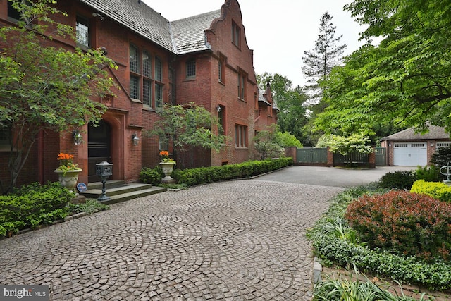 view of home's community with decorative driveway and fence