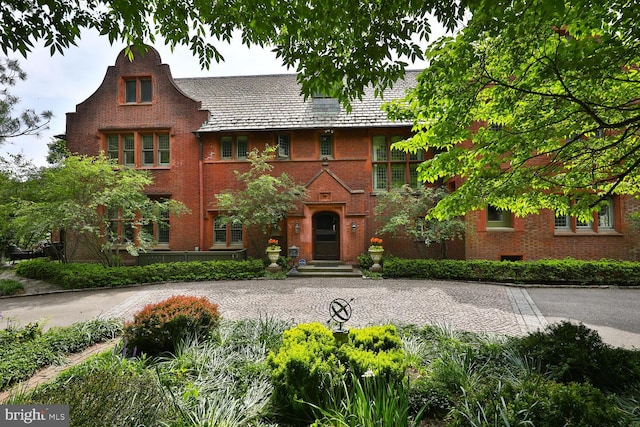 tudor home featuring a high end roof and brick siding