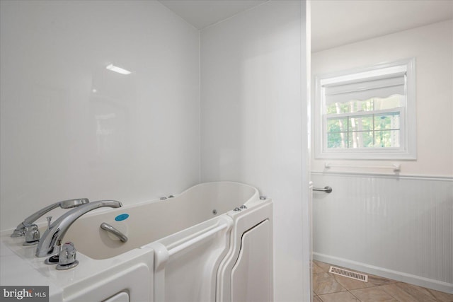 bathroom with tile patterned flooring and a tub