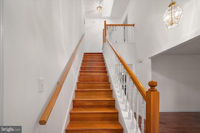 staircase featuring wood-type flooring and a notable chandelier