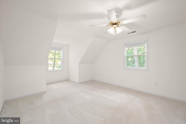 additional living space featuring light carpet, vaulted ceiling, a wealth of natural light, and ceiling fan