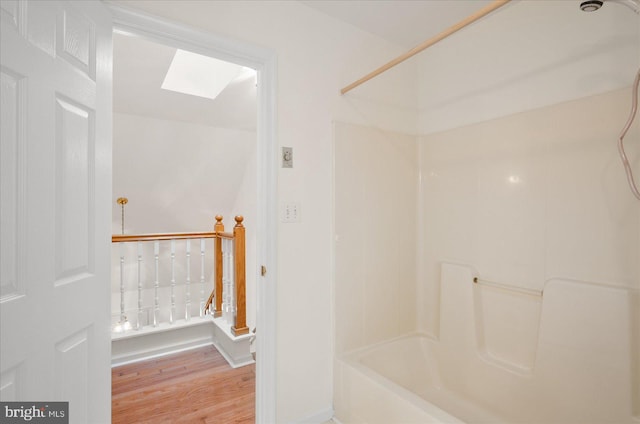 bathroom featuring  shower combination, wood-type flooring, and a skylight