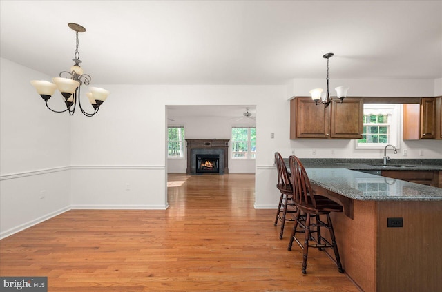 kitchen with pendant lighting, a notable chandelier, sink, and light hardwood / wood-style floors