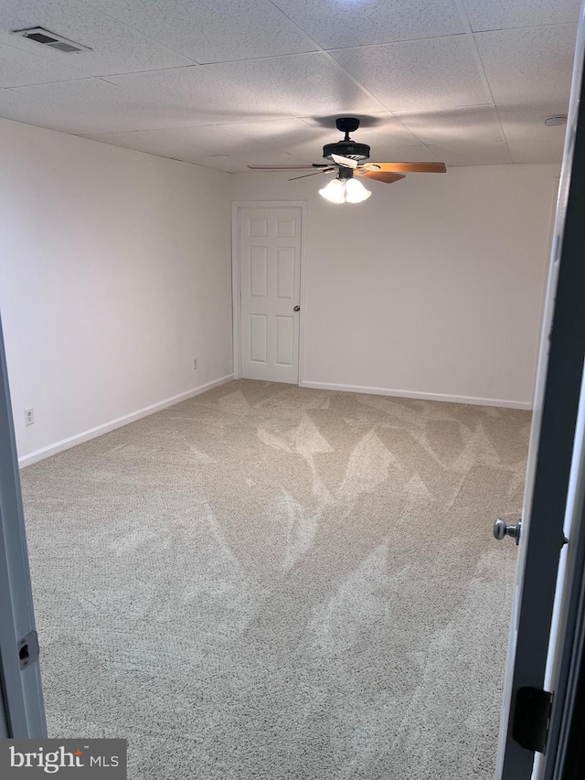 carpeted empty room with visible vents, baseboards, a paneled ceiling, and ceiling fan