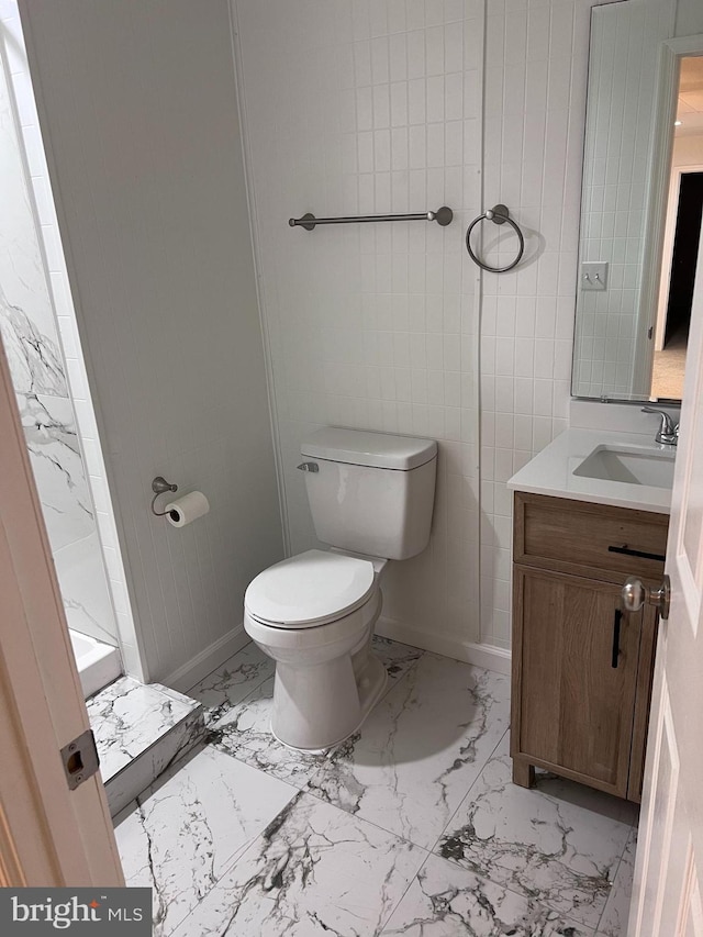 bathroom with vanity, toilet, baseboards, and marble finish floor