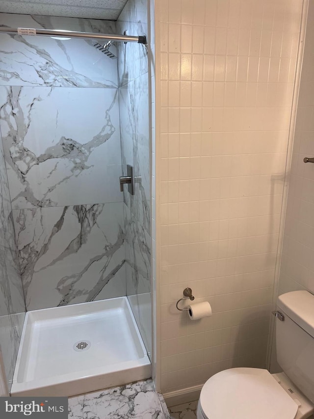 full bath with a marble finish shower and toilet