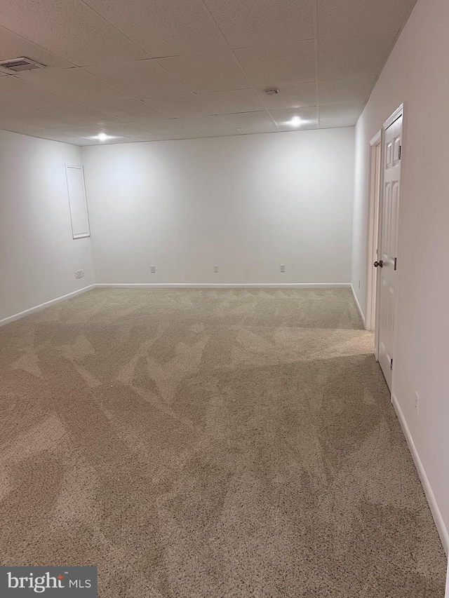 empty room featuring a drop ceiling, baseboards, visible vents, and carpet flooring