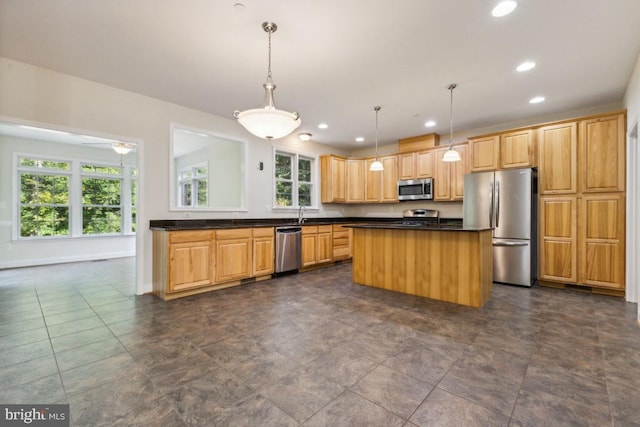 kitchen with stainless steel appliances, a kitchen island, and decorative light fixtures