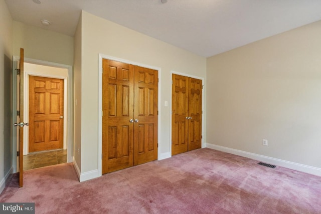 unfurnished bedroom featuring two closets and carpet