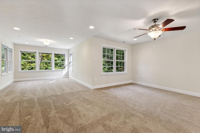 carpeted spare room featuring ceiling fan and a healthy amount of sunlight