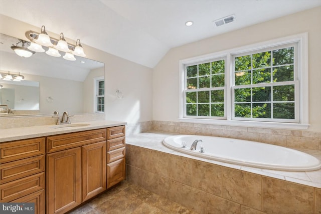 bathroom with a relaxing tiled tub, vanity, lofted ceiling, and plenty of natural light