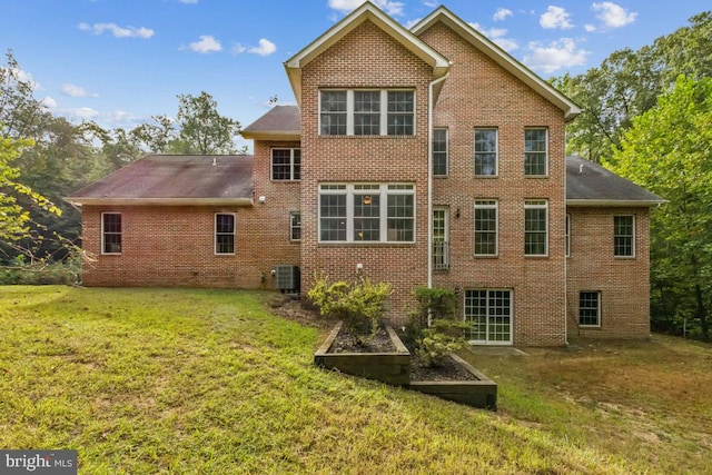 back of house featuring central AC unit and a lawn