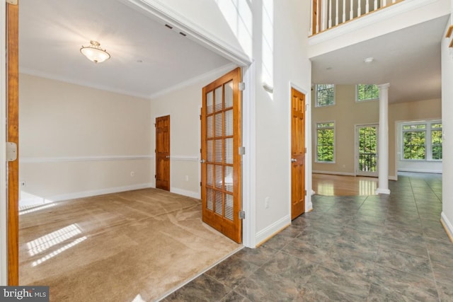 carpeted empty room with decorative columns and ornamental molding