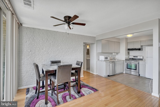 dining space featuring a textured ceiling, light hardwood / wood-style floors, sink, and ceiling fan