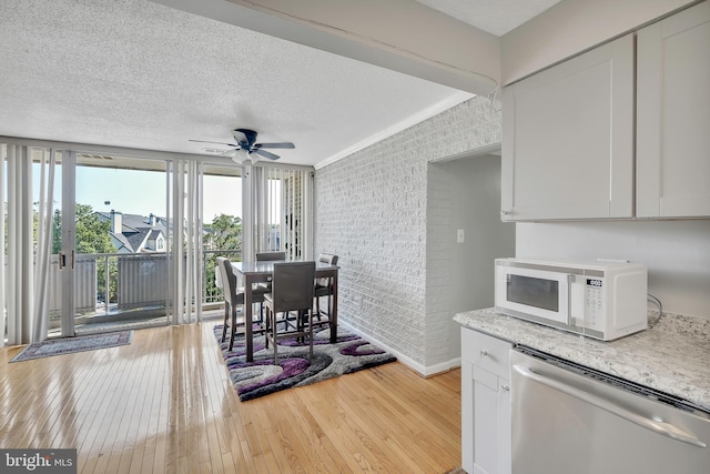 dining area featuring light hardwood / wood-style floors, brick wall, a textured ceiling, crown molding, and ceiling fan