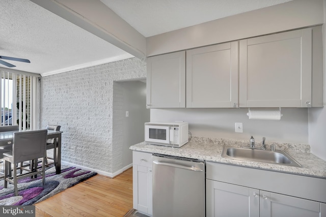 kitchen with light hardwood / wood-style floors, a textured ceiling, ceiling fan, stainless steel dishwasher, and sink