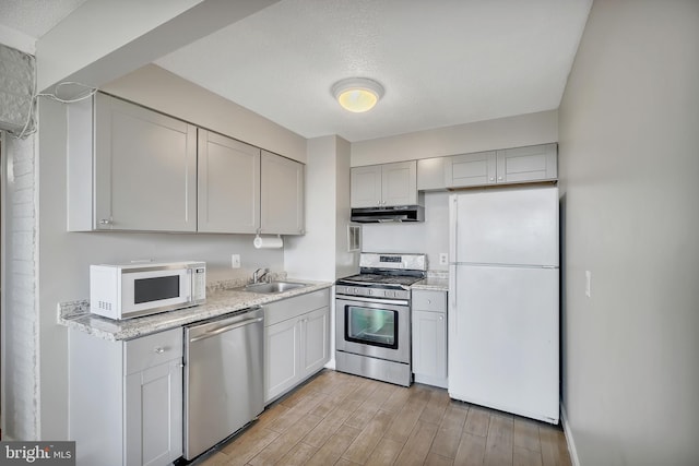 kitchen with stainless steel appliances, light hardwood / wood-style floors, a textured ceiling, and sink