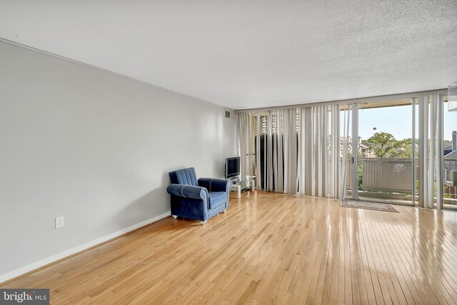 living area featuring a textured ceiling, hardwood / wood-style floors, and expansive windows