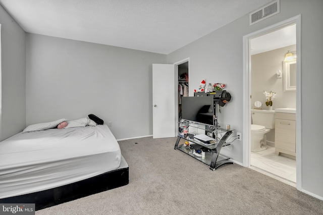 bedroom featuring ensuite bath, a textured ceiling, and carpet floors