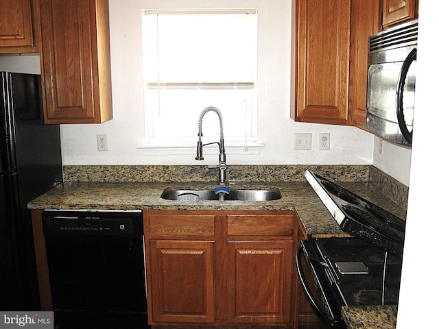 kitchen featuring black appliances, dark stone countertops, and sink