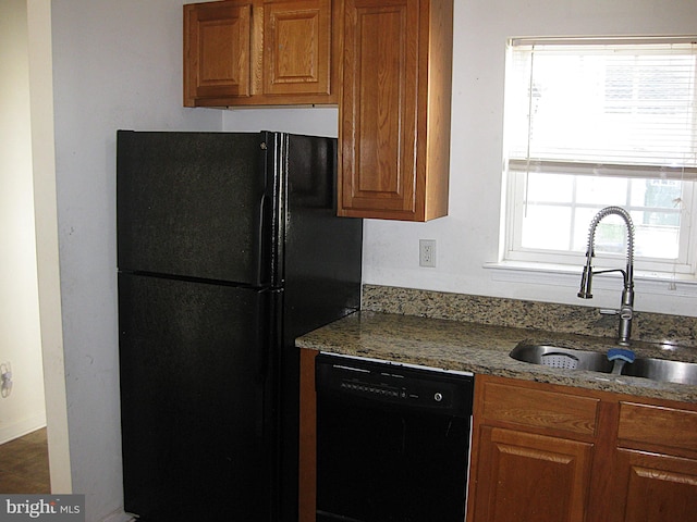 kitchen featuring black appliances, sink, and light stone countertops