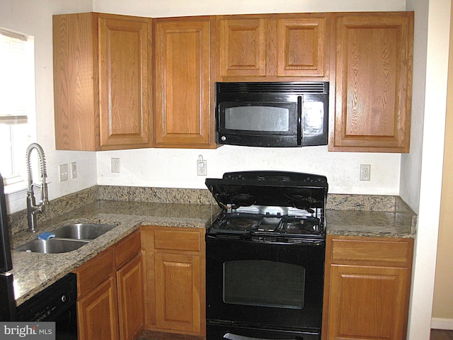 kitchen featuring black appliances, light stone counters, and sink