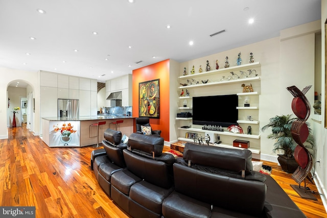 living room featuring visible vents, baseboards, light wood-type flooring, recessed lighting, and arched walkways