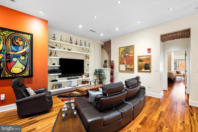 living room with light wood-type flooring and built in shelves