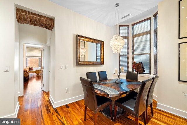 dining area with hardwood / wood-style flooring and an inviting chandelier