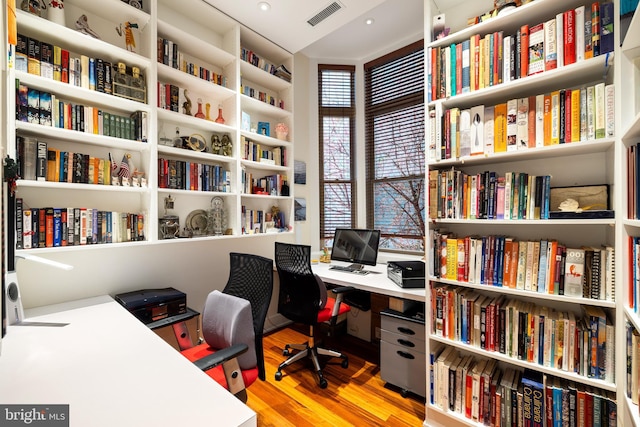 office area with visible vents, wood finished floors, and bookshelves