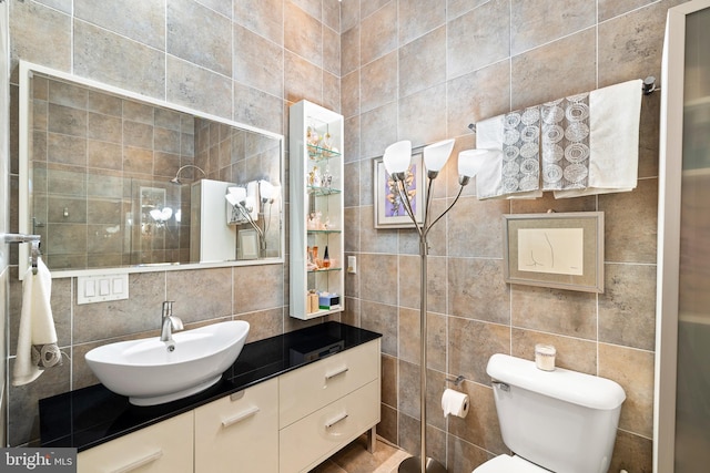 bathroom featuring toilet, tasteful backsplash, tile walls, tiled shower, and vanity